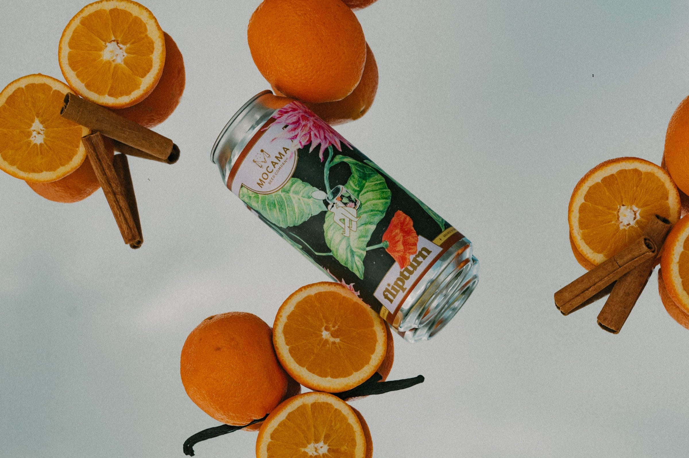 A flipturn can surrounded by oranges, cinnamon sticks and vanilla